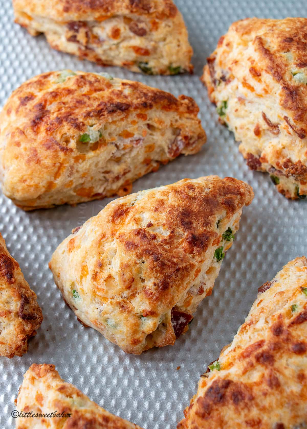 A close-up of bacon cheddar scones on a silver baking tray.