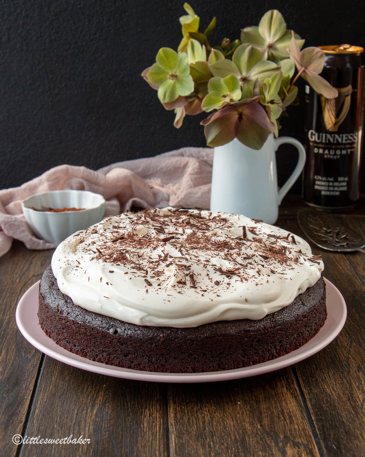 Chocolate Guinness Cake topped with cream cheese frosting on a pink plate.