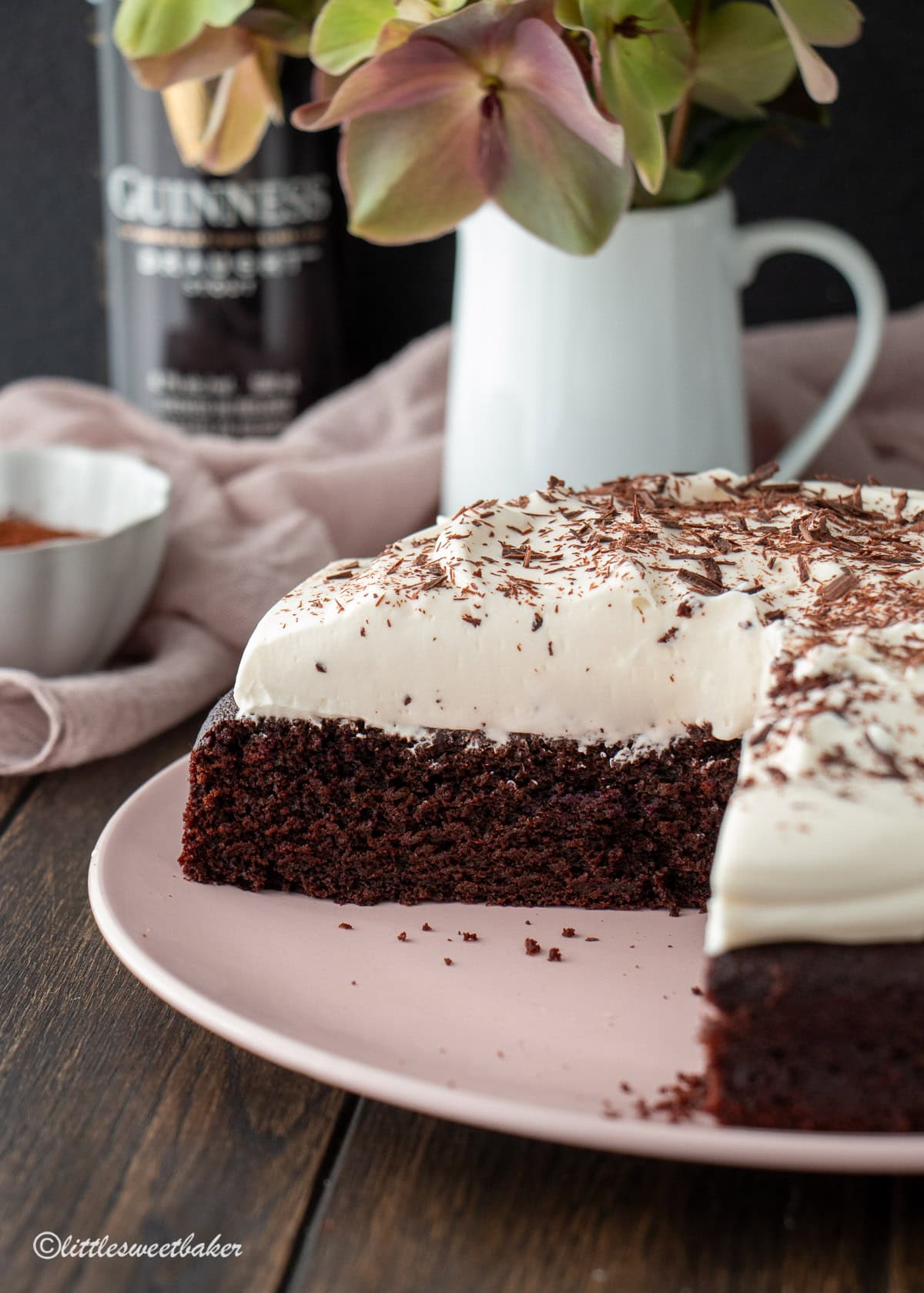 The inside of a chocolate Guinness cake topped with cream cheese frosting on a pink plate.