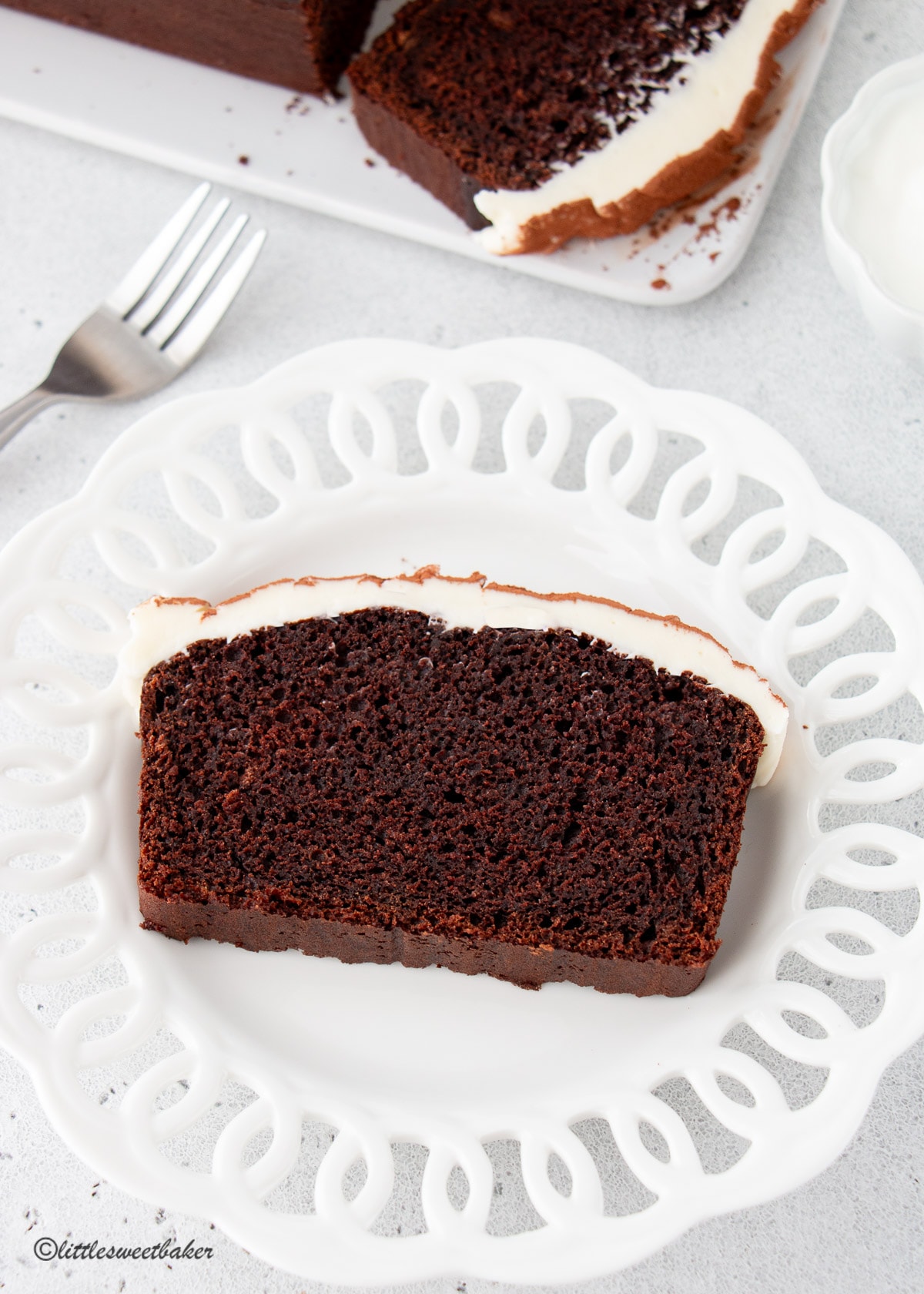 A slice of chocolate Guinness cake topped with cream cheese frosting on a white dessert plate.