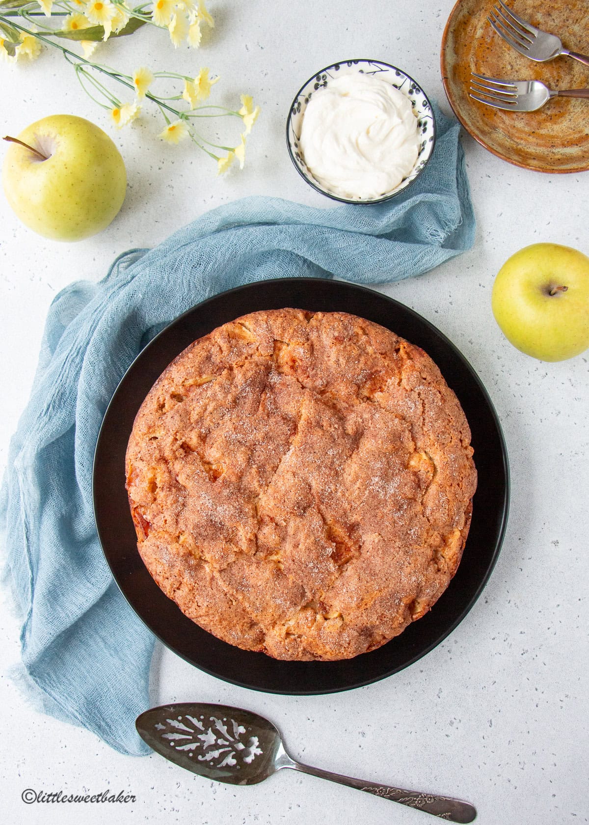 An Irish apple cake on a black plate with a blue chiffon napkin.