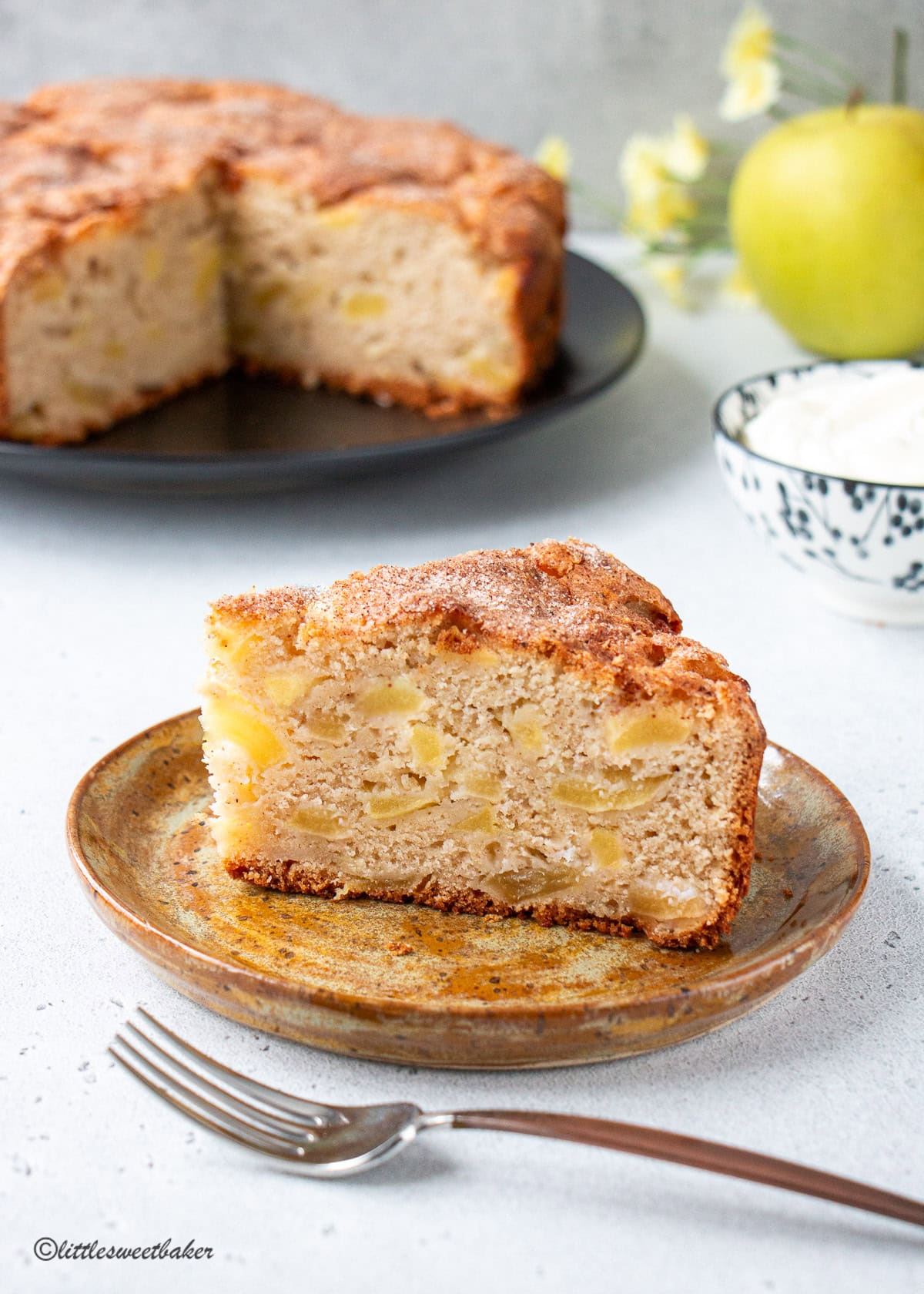 A slice of Irish apple cake on a pottery place with a copper handle fork.