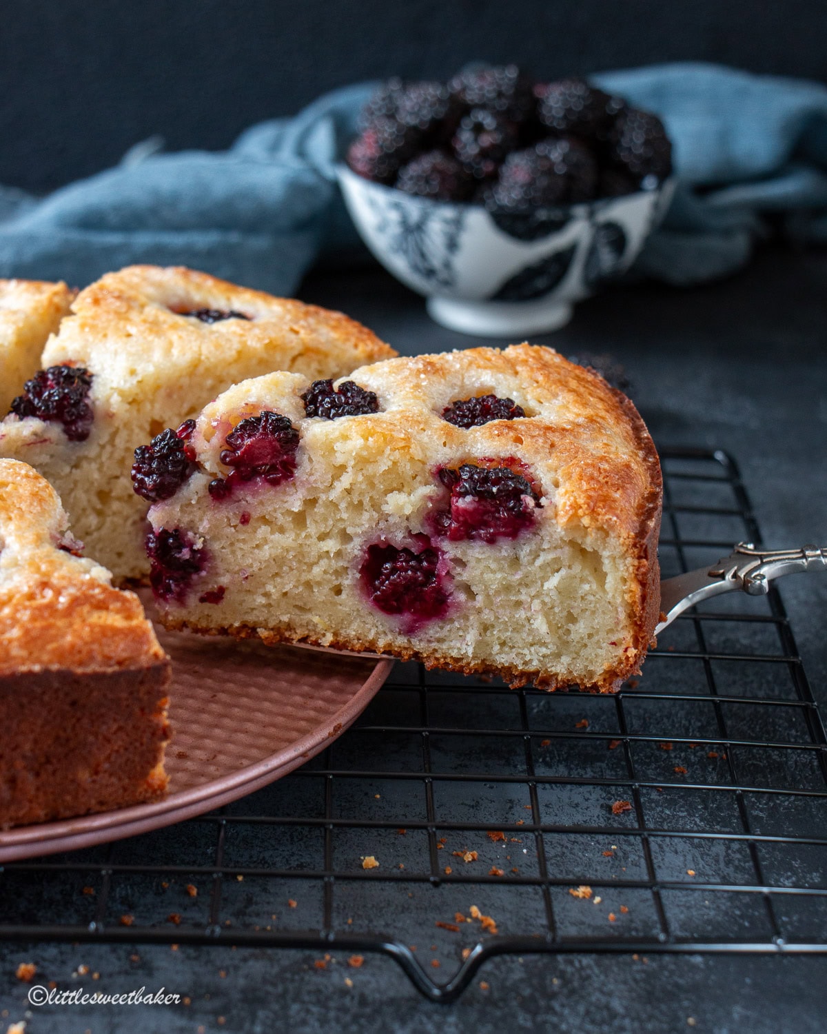 A slice of blackberry cake being removed from the rest of the cake.