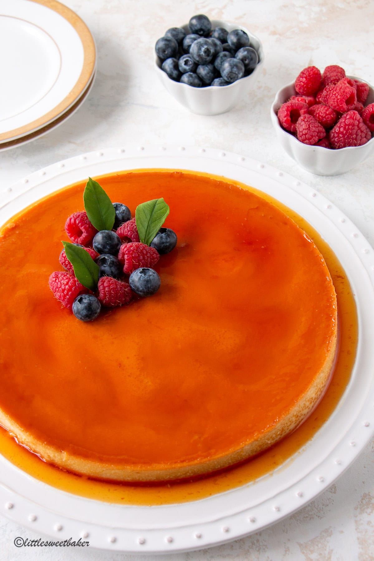 A whole Mexican plan topped with berries and lemon leaves on a white serving plate.