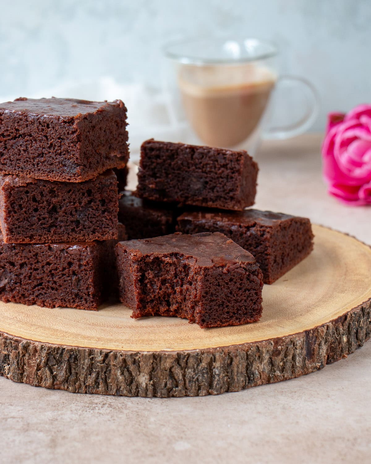 Mochi brownies on a wooden board with a bite taken out of one of them.