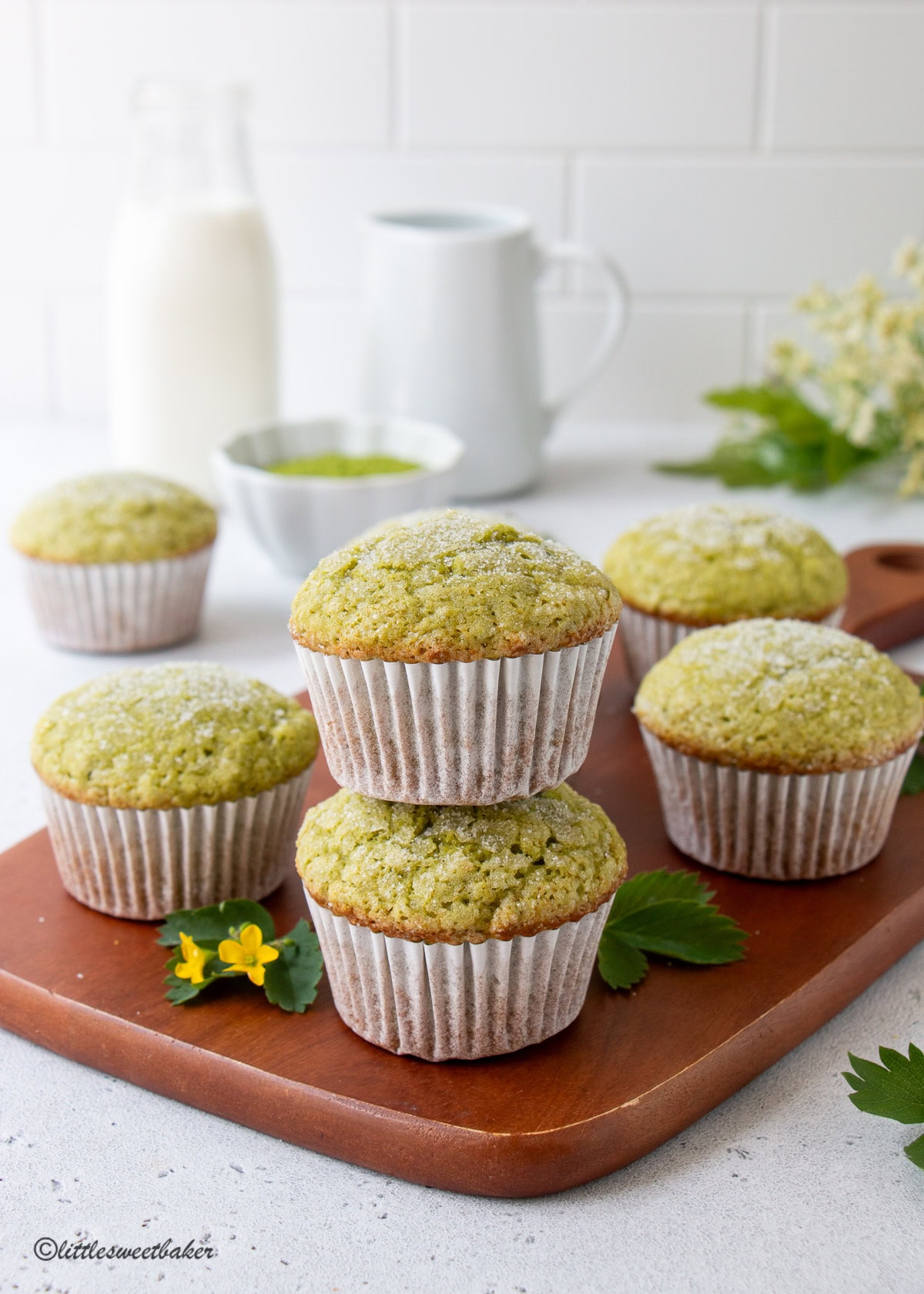 Matcha muffins on a wooden cutting board with two stacked together.