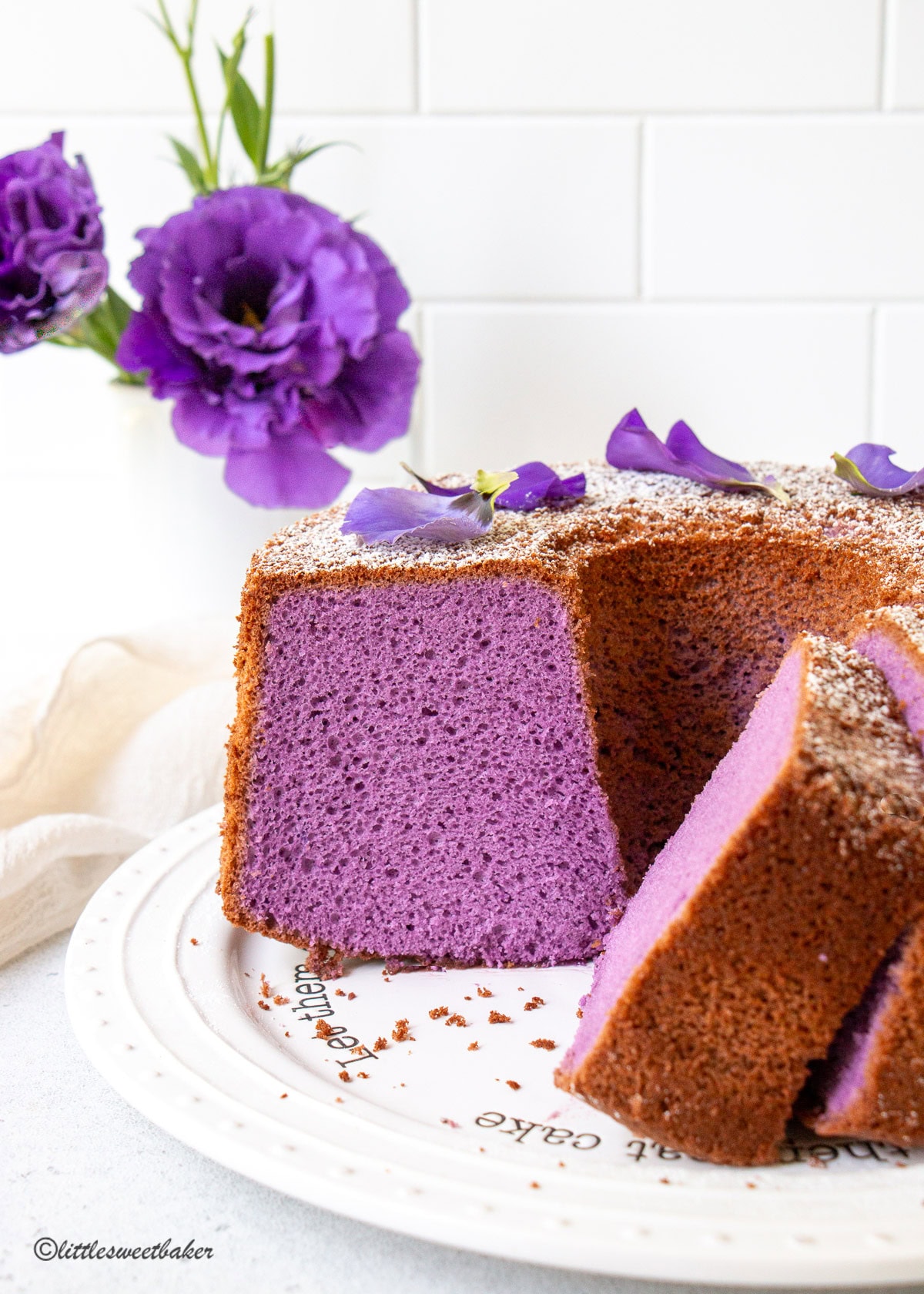 An ube chiffon cake with a few slices cut on a white plate.
