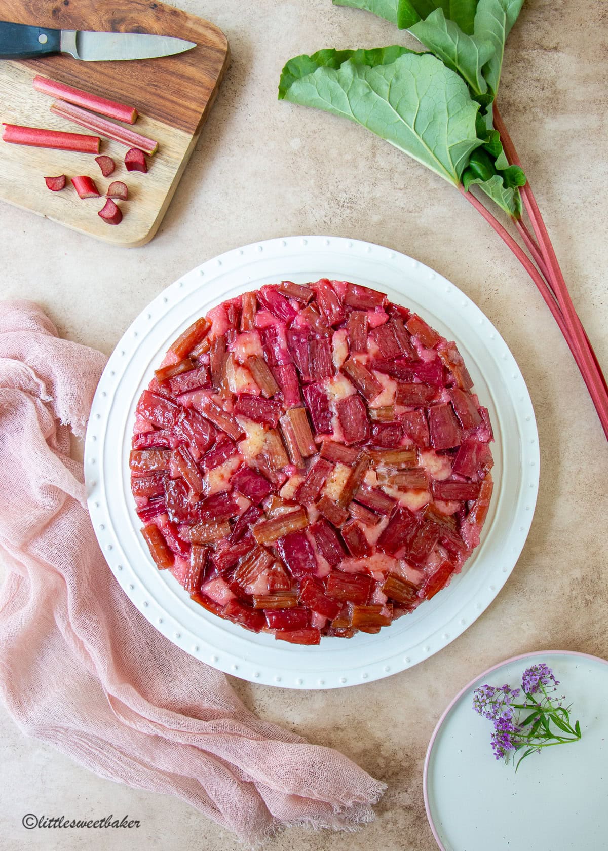 A top view of a rhubarb upside-down cake on a white plate.