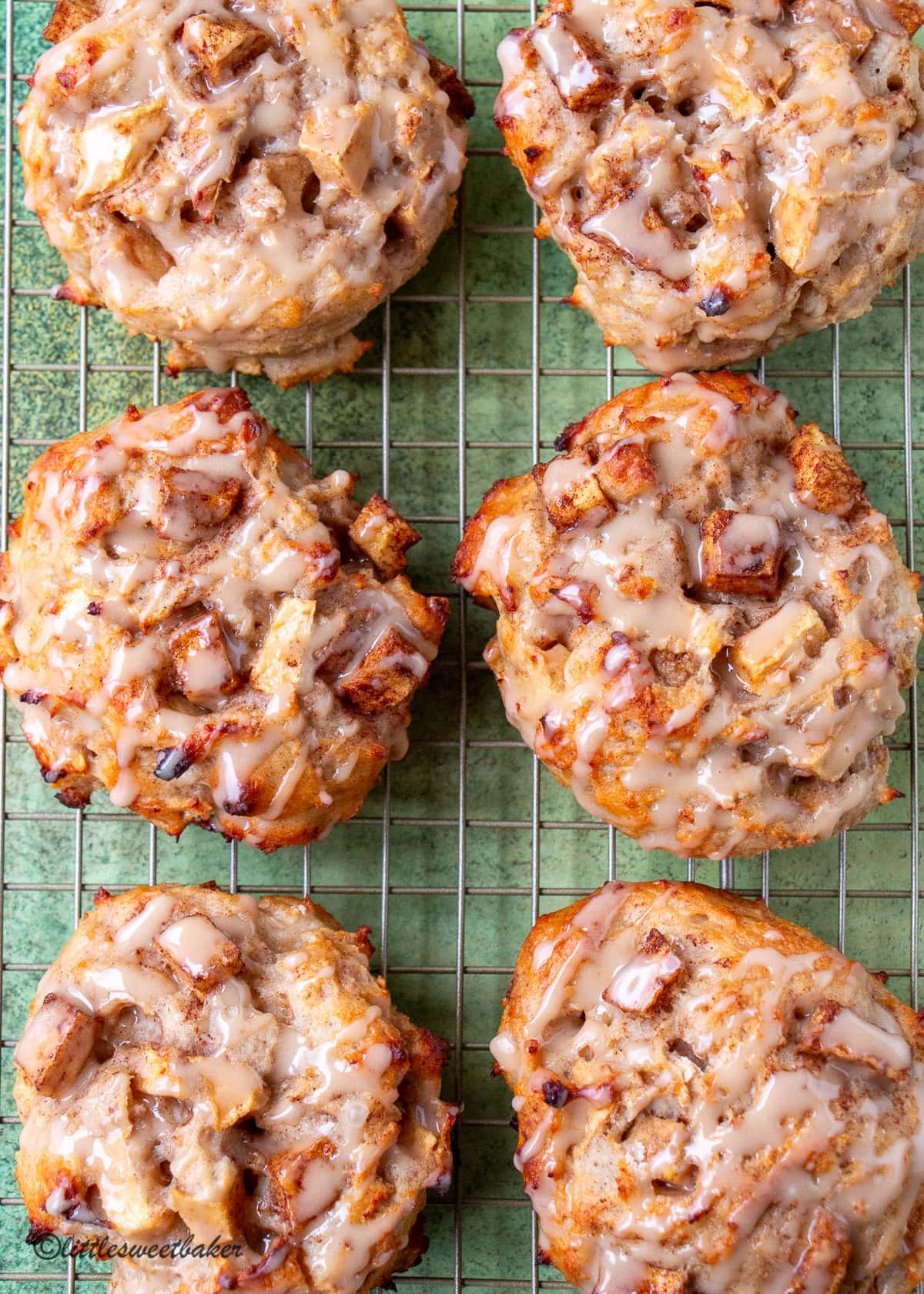 Glazed baked apple fritters on a cooling rack.