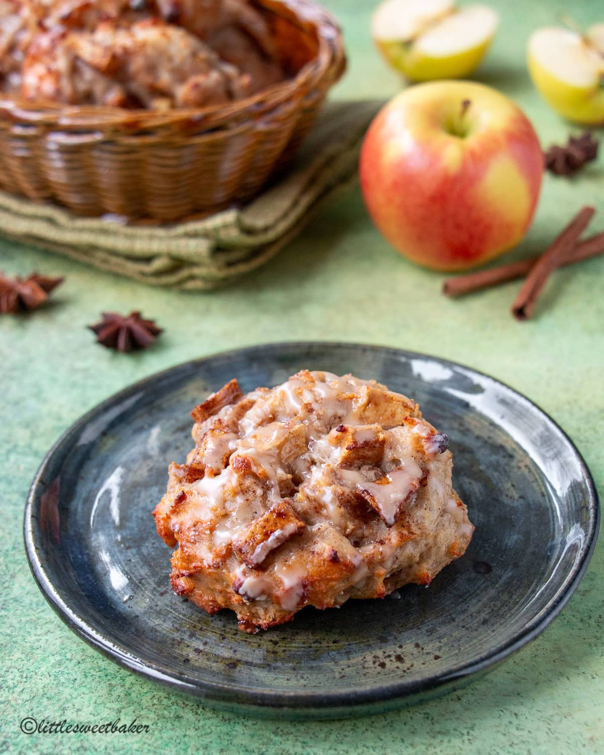 A baked apple fritter on a grayish-blue pottery plate.
