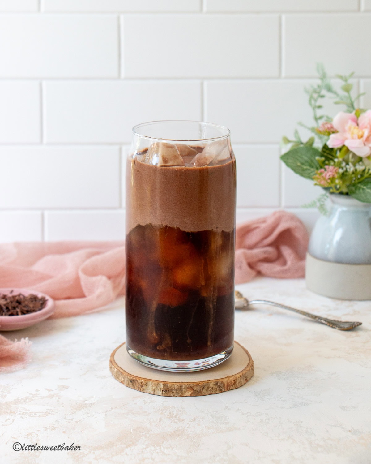 A glass of iced coffee topped with chocolate protein cold foam.