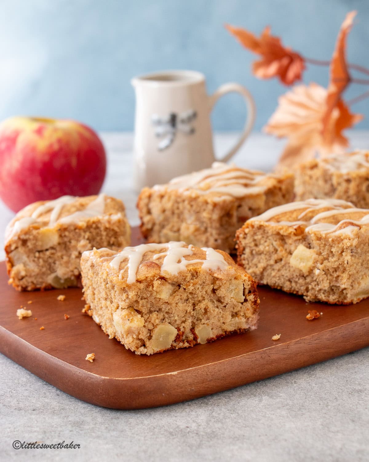 Healthy Apple Cake topped with glaze on a wooden board.
