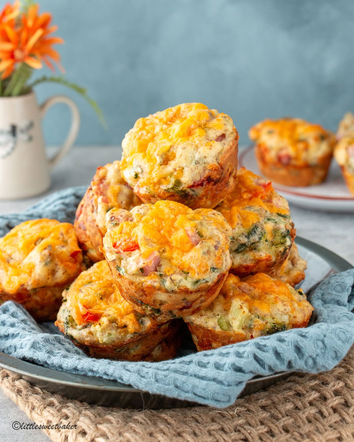 Savory breakfast muffins piled into a pie plate with a blue napkin.