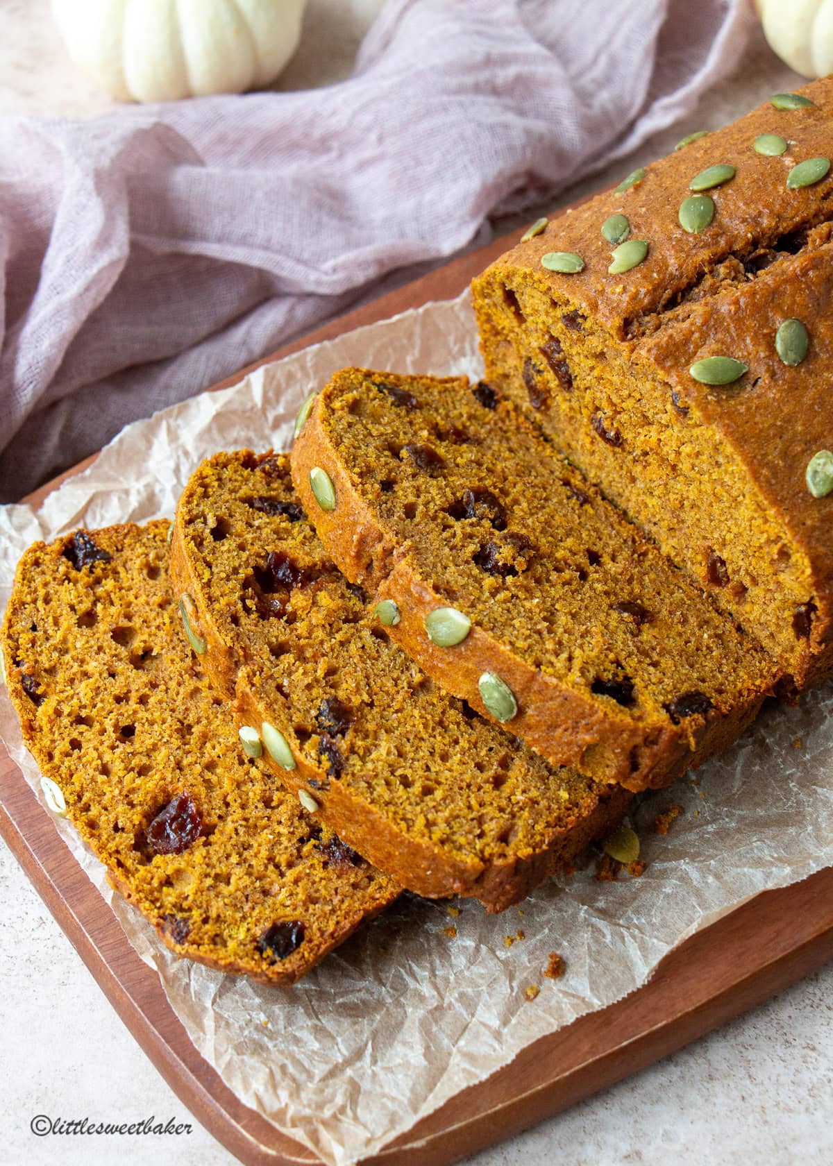 A loaf of healthy pumpkin bread on a wooden cutting board with a few slices cut.