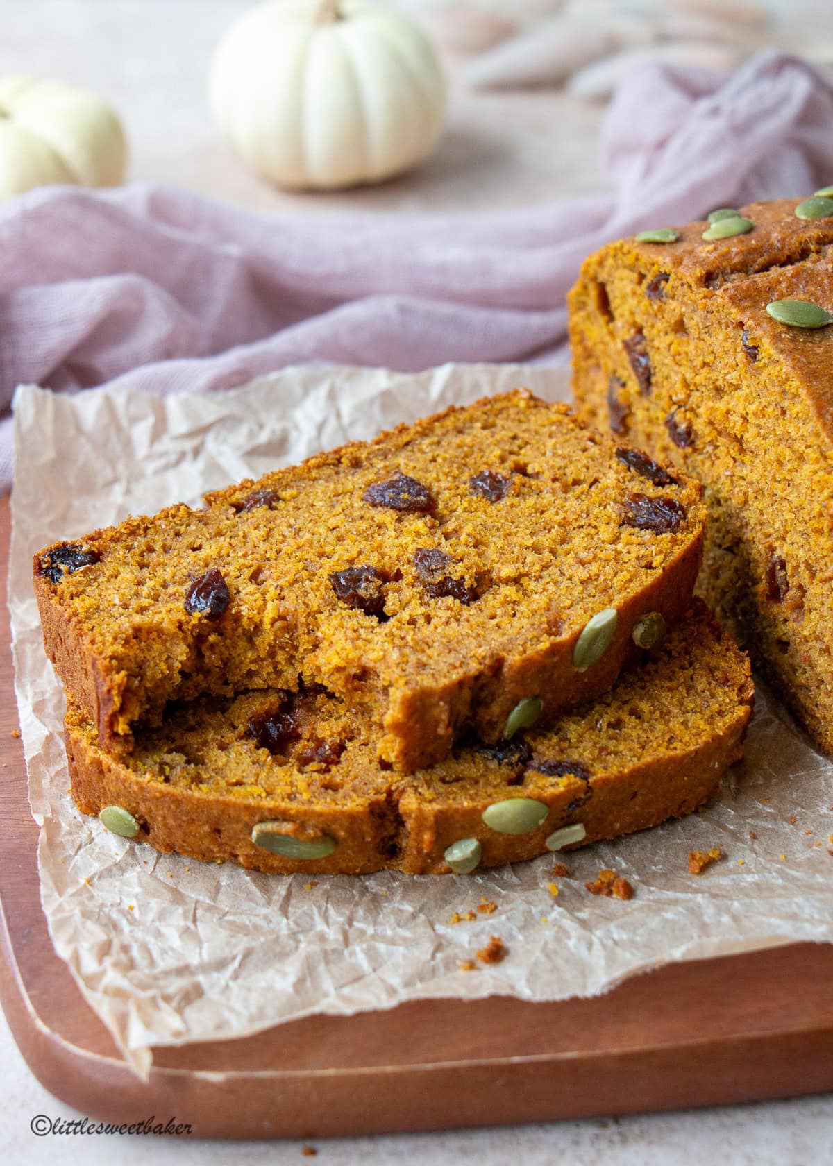 Two slices of healthy pumpkin bread on a cutting board with a bite taken out of the top slice.