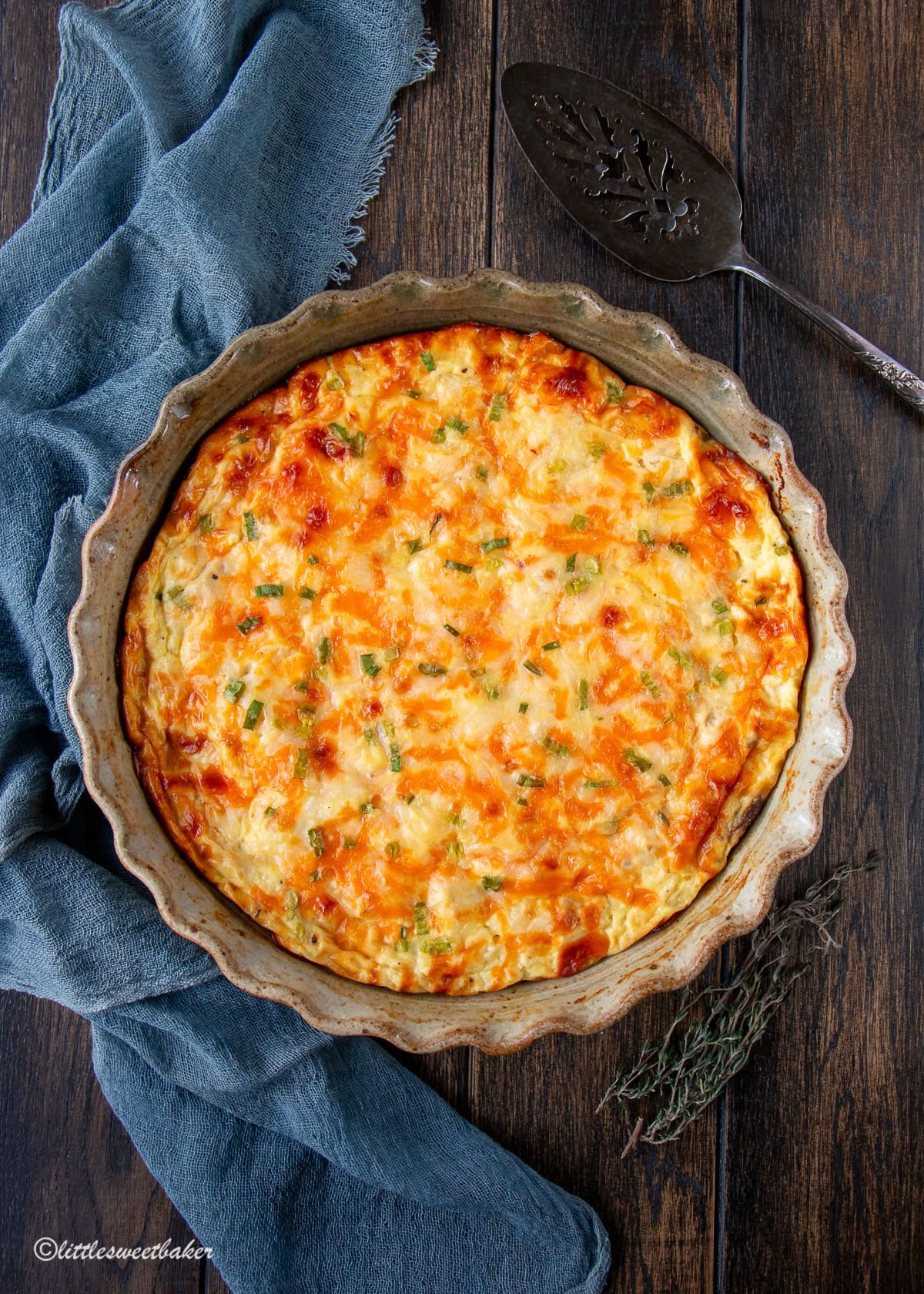 A crustless cottage cheese quiche on a wooden table with a blue napkin and server.