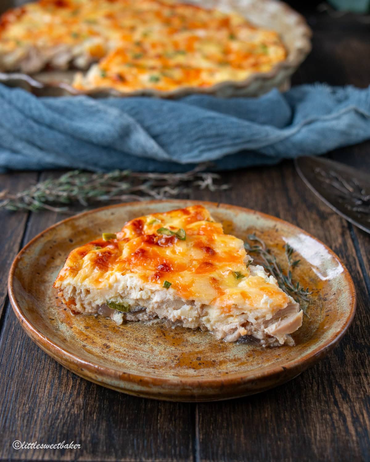 A slice of crustless cottage cheese quiche on a small brown pottery plate.