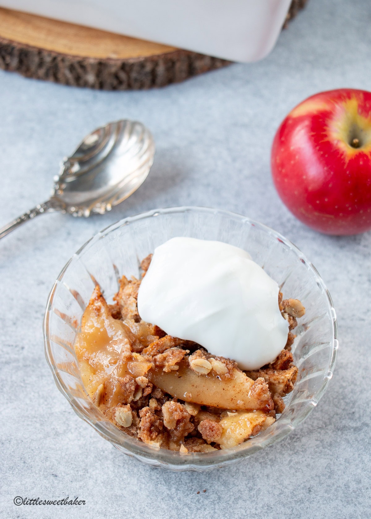 A glass bowl of healthy apple crisp topped with yogurt.