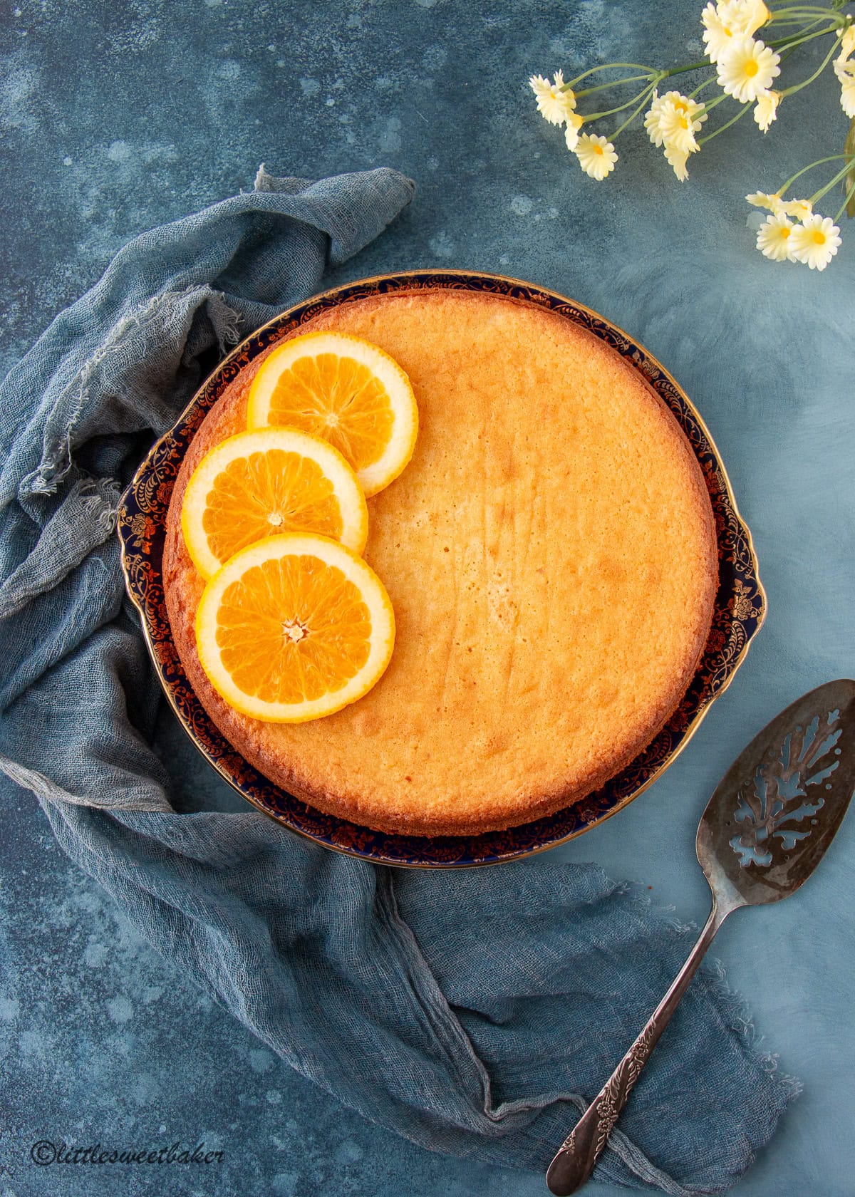 Orange almond flour cake topped with orange slices on a vintage plate.