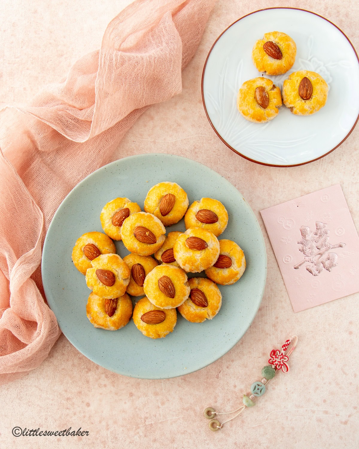 Two plates of Chinese almond cookies on a pink surface.