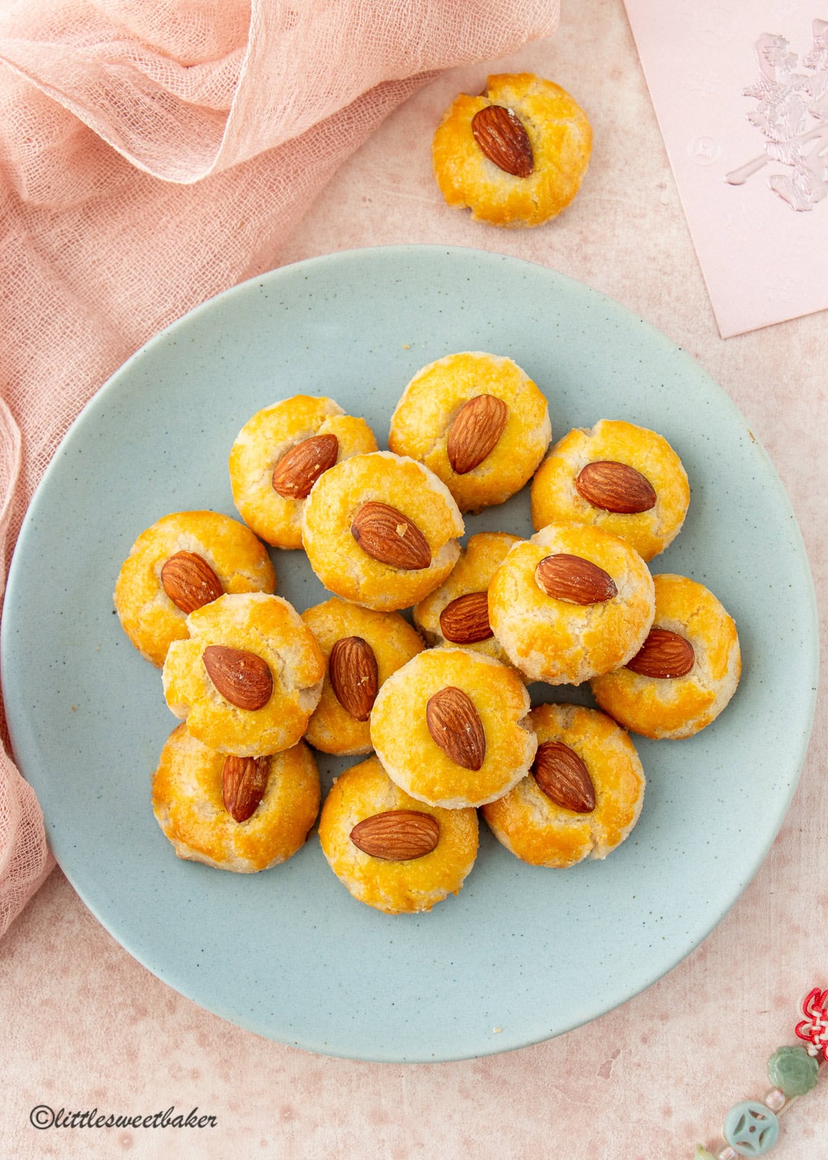 A blue plate of Chinese Almond Cookies on a pink surface.