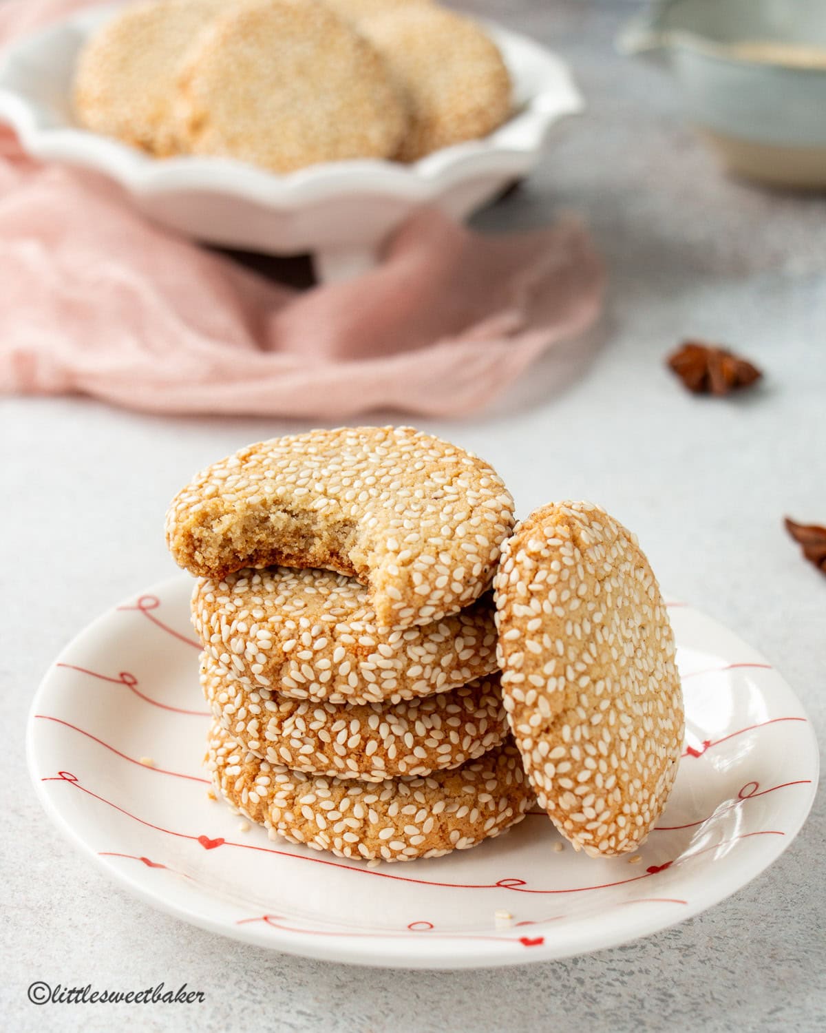 Honey sesame cookies stacked on a small plate with the top one missing a bite.