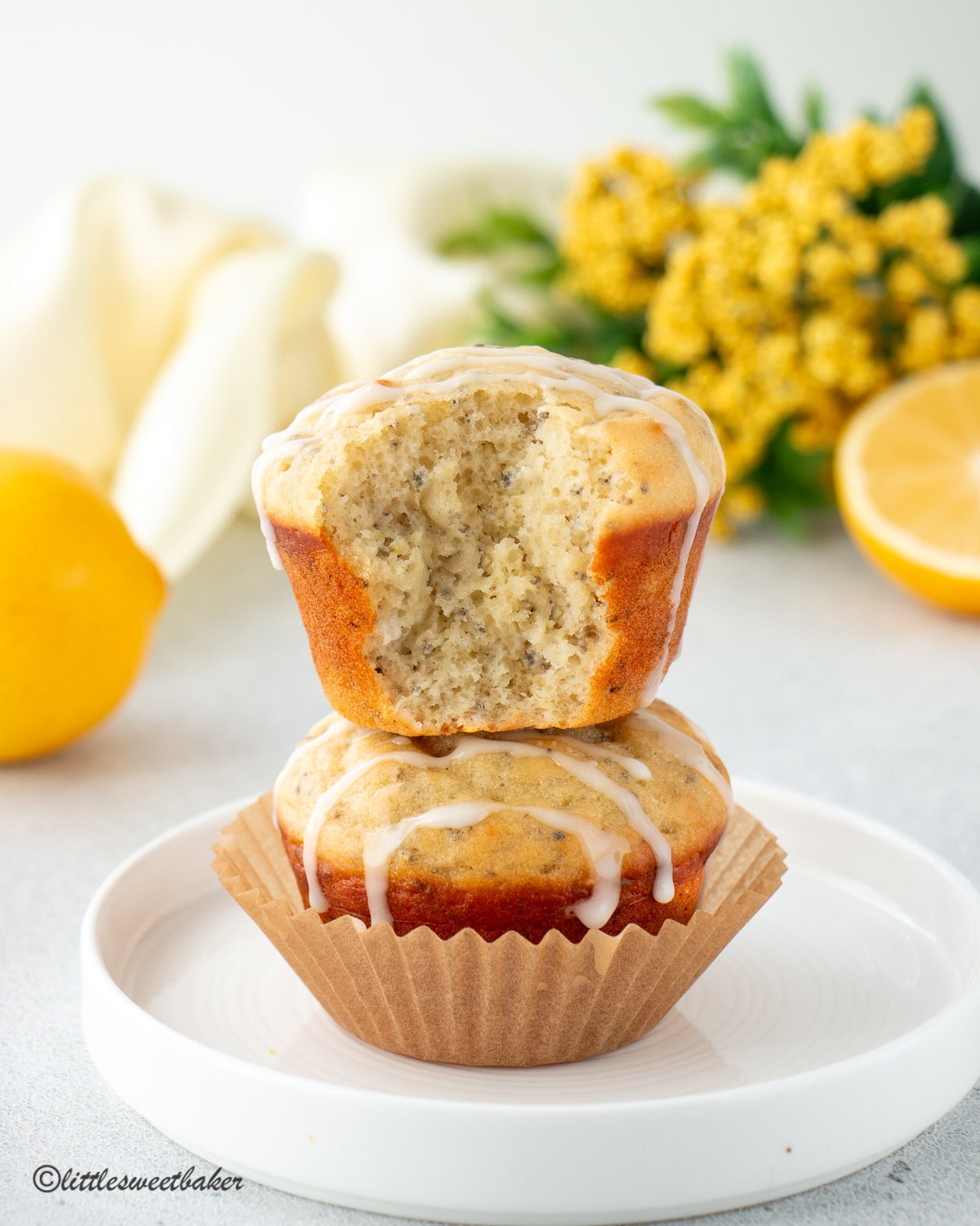 Two lemon chia seed muffins stacked with the top one missing a bite.