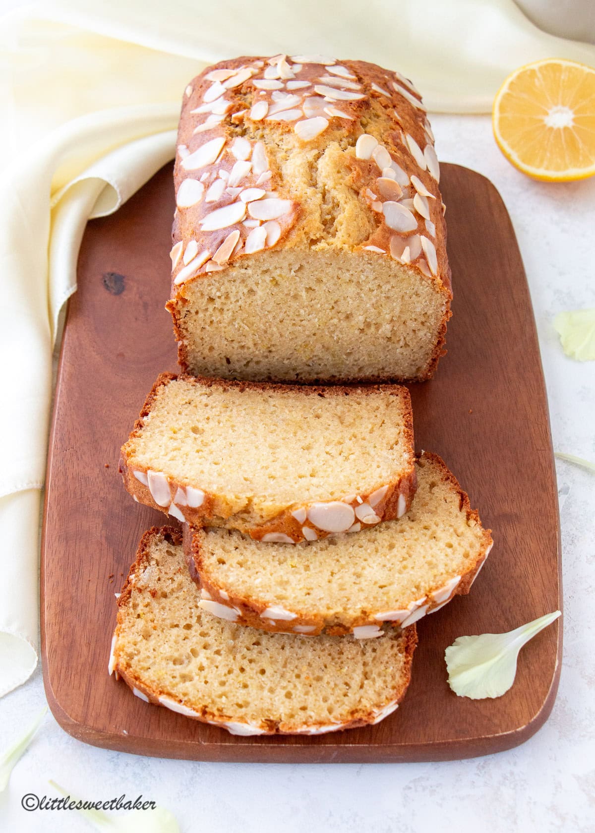 A healthy lemon loaf with a few slices cut on a wooden cutting board.