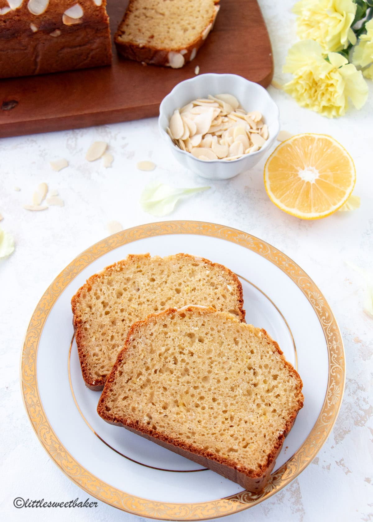 Two slices of healthy lemon loaf on a white and gold plate.