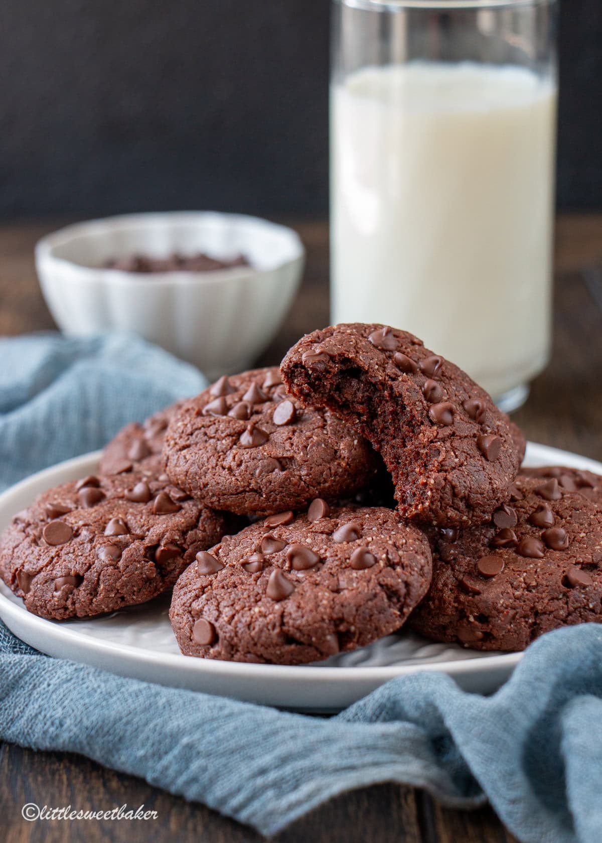 A plate of healthy double chocolate cookies with one cookie missing a bite.