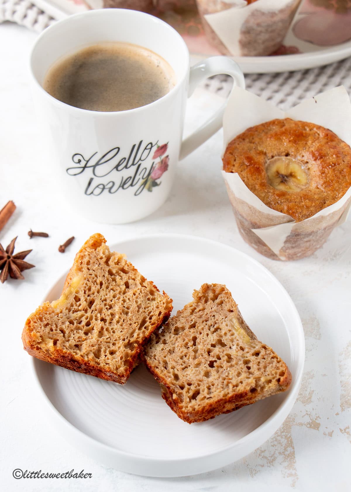 A high-protein banana muffin cut in half on a white plate.