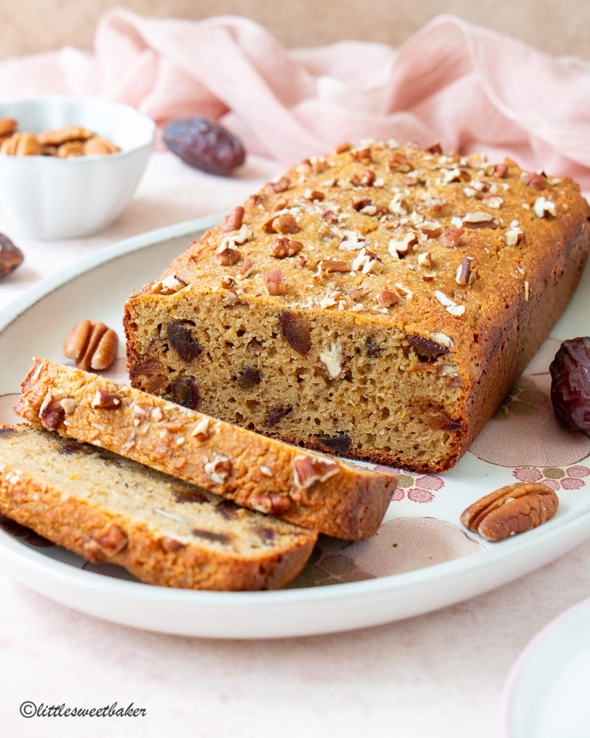 Healthy orange date cake on a floral platter with two slices cut.