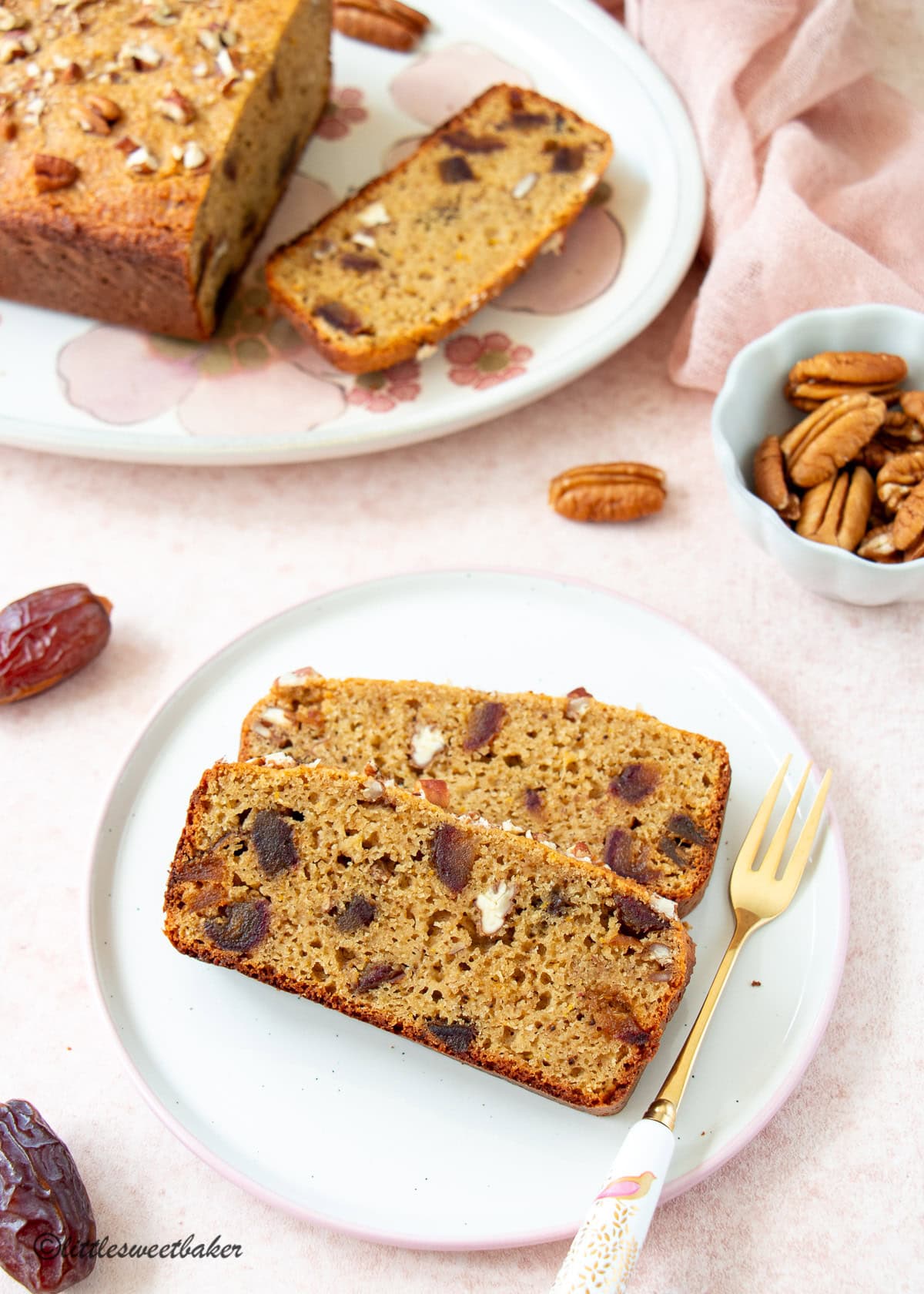 Two slices of healthy orange date cake on a plate with a small gold dessert fork.
