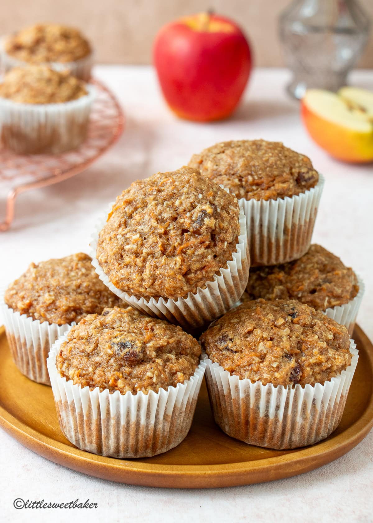 Healthy carrot cake muffins piled on a small wooden plate.