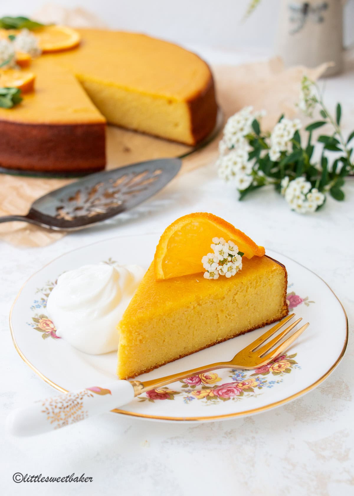 A slice of whole orange custard cake served with a dollop of whipped cream.