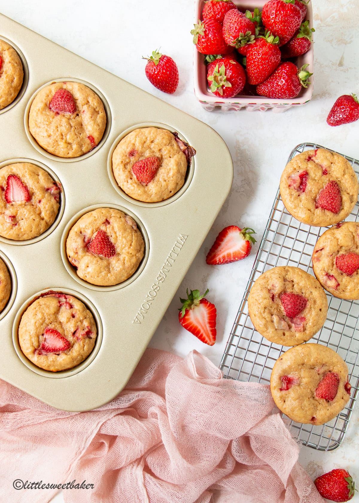 High-protein strawberry muffins on a cooling rack and gold muffin pan.