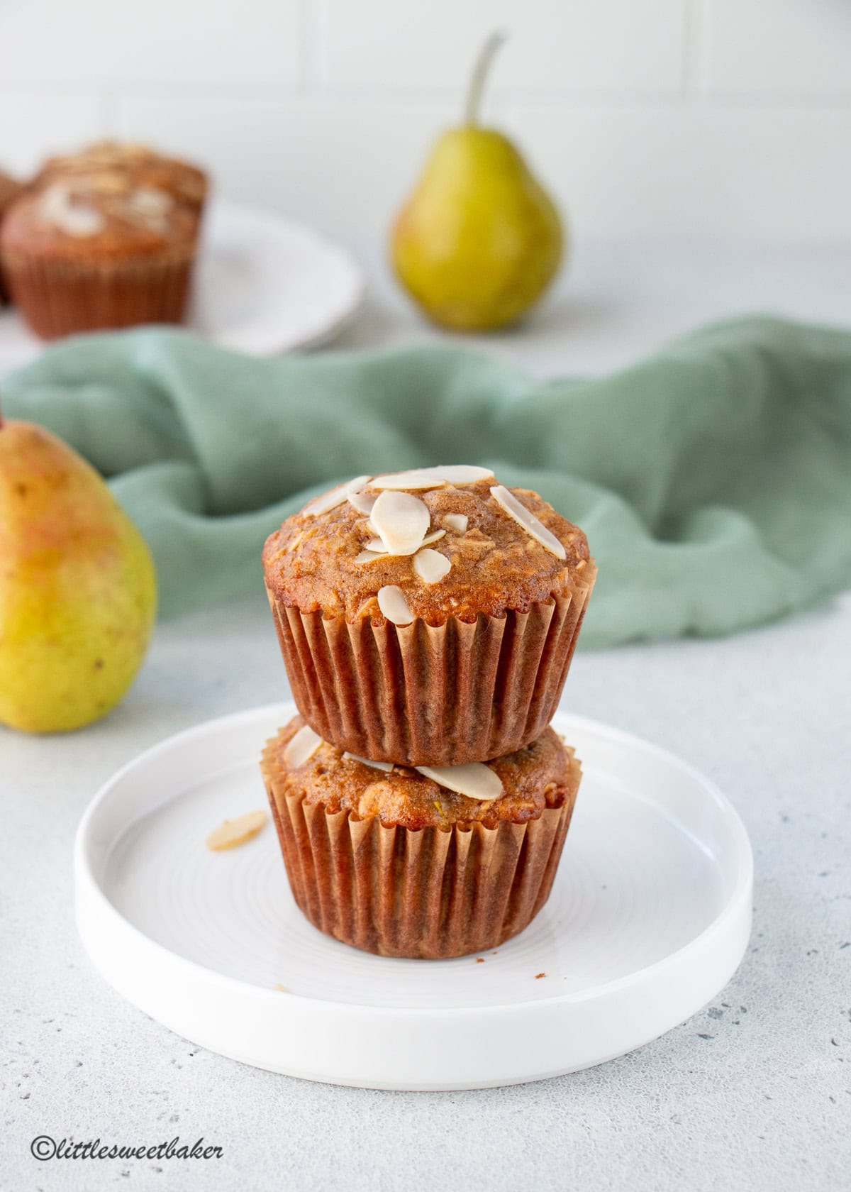 Two healthy pear muffins stacked on a small white plate.